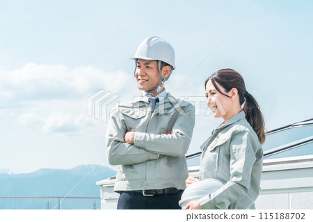 An engineer/business person in work clothes from an electric power company/electrical contractor standing in front of a solar power generation/solar panel 115188702