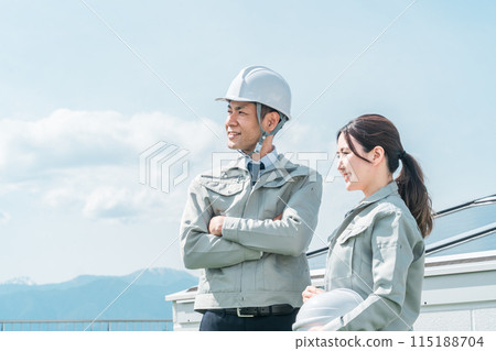 An engineer/business person in work clothes from an electric power company/electrical contractor standing in front of a solar power generation/solar panel 115188704