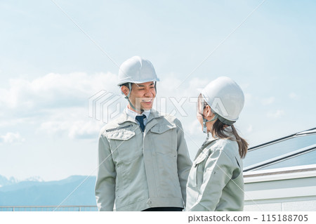 An engineer/business person in work clothes from an electric power company/electrical contractor standing in front of a solar power generation/solar panel 115188705