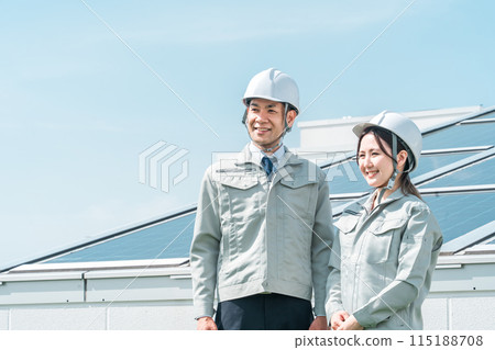 An engineer/business person in work clothes from an electric power company/electrical contractor standing in front of a solar power generation/solar panel An engineer/business person in work clothes from an electric power company/electrical contractor standing in front of a solar power generation/solar panel 115188708