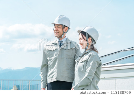 An engineer/business person in work clothes from an electric power company/electrical contractor standing in front of a solar power generation/solar panel 115188709