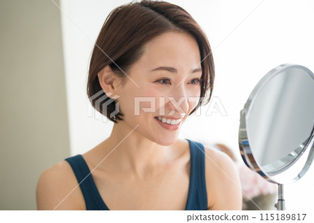 Woman in her forties looking in the mirror 115189817