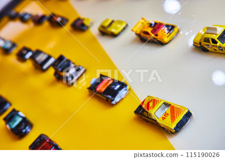 Black and yellow toy cars on shiny white and yellow background split diagonally Black and yellow toy cars on shiny white and yellow background split diagonally 115190026
