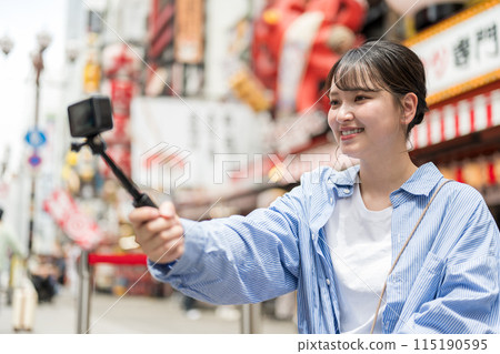 Young and pretty woman taking a selfie in the city's downtown area | Osaka Tourism Image | Dotonbori Shopping Street, Osaka City, Osaka Prefecture Young and pretty woman taking a selfie in the city's downtown area | Osaka Tourism Image | Dotonbori Shopping Street, Osaka City, Osaka Prefecture 115190595