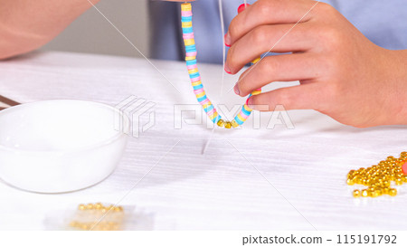 Delicate fingers of a young girl navigate through a treasure trove of bright, multicolored beads, each compartment revealing a new hue to choose from. She's immersed in the joyful task of stringing Delicate fingers of a young girl navigate through a treasure trove of bright, multicolored beads, each compartment revealing a new hue to choose from. She's immersed in the joyful task of stringing 115191792