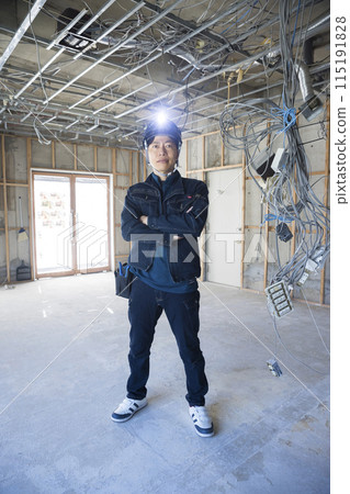 A male worker wearing fashionable denim work clothes and standing at a construction site 115191828