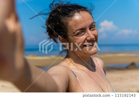 A woman in a swimsuit takes a selfie on the beach A woman in a swimsuit takes a selfie on the beach 115192143