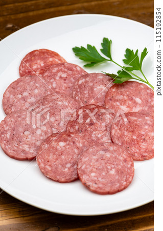 Salami on a white plate on a wooden table Salami on a white plate on a wooden table 115192854