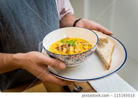 A bowl of pumpkin porridge with tofu and vegetables 115193018