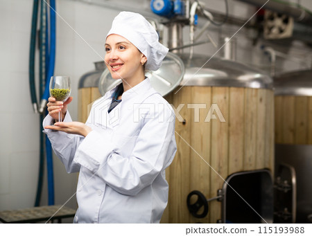 Portrait of woman brewmaster holding glass of hops pellets Portrait of woman brewmaster holding glass of hops pellets 115193988