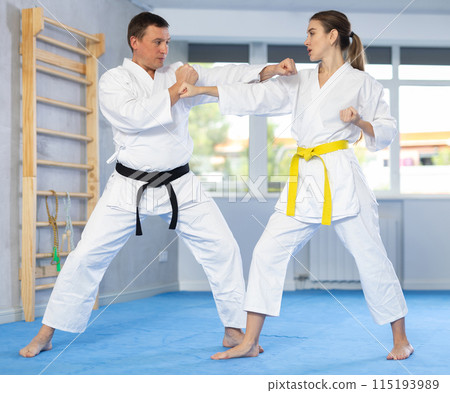 Adult man and young woman training karate fight Adult man and young woman training karate fight 115193989