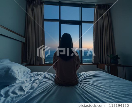 A woman unable to sleep and looking out the window 115194120