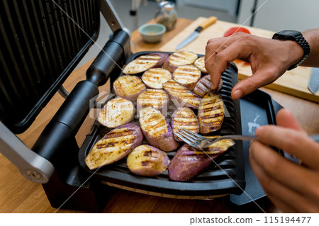 Chef at the kitchen preparing grilled eggplants with garlic 115194477