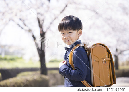 First grade elementary school students carrying backpacks and rows of cherry blossom trees - an image of school entrance First grade elementary school students carrying backpacks and rows of cherry blossom trees - an image of school entrance 115194961