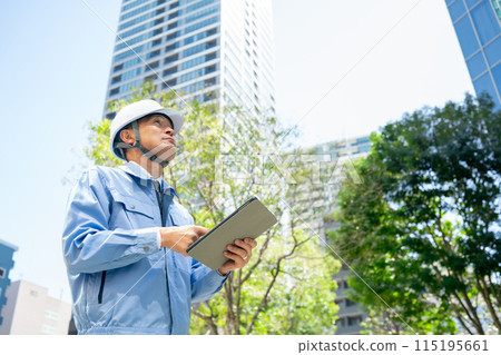 Man in work clothes, office building, looking up Man in work clothes, office building, looking up 115195661