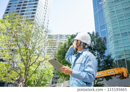 穿著工作服的男人抬頭看著辦公大樓指著 穿著工作服的男人抬頭看著辦公大樓指著 115195665