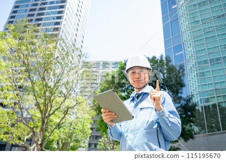 穿著工作服的男人抬頭看著辦公大樓，拳頭泵 115195670
