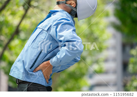 Man in work clothes stretching waist Man in work clothes stretching waist 115195682