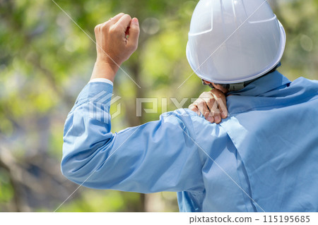Man in work clothes stretching shoulders up Man in work clothes stretching shoulders up 115195685