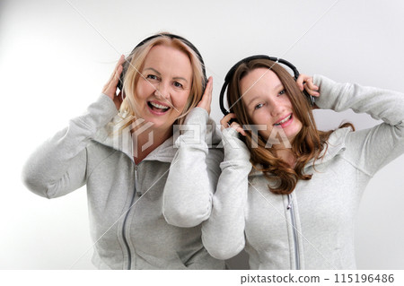 woman and girl mother and daughter listening to music on headphones dancing in the same clothes two generations mutual understanding friends on a white background dancing girl singing woman and girl mother and daughter listening to music on headphones dancing in the same clothes two generations mutual understanding friends on a white background dancing girl singing 115196486