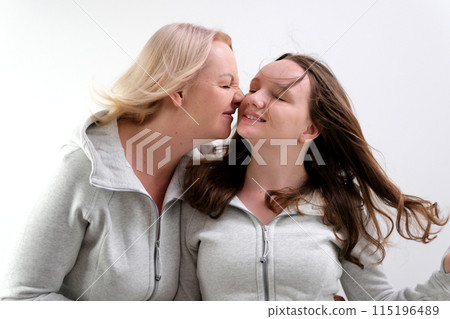 Adorable lovely fun satisfied elder parent mom with young adult daughter two women together wearing casual clothes hugging cuddle close eyes isolated on plain blue cyan background. Family day concept Adorable lovely fun satisfied elder parent mom with young adult daughter two women together wearing casual clothes hugging cuddle close eyes isolated on plain blue cyan background. Family day concept 115196489