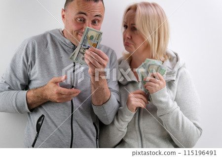 surprise on the face Men have a lot of money in their hands bake their lower lip woman wants more than 100 dollar bills husband wife emotions middle age man and woman with money on white background 115196491