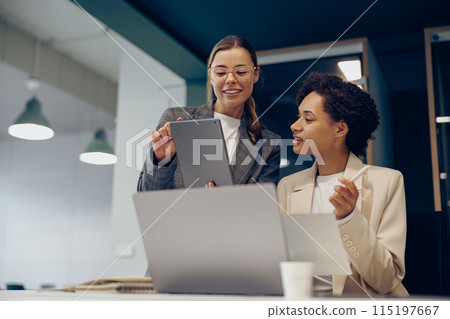 Smiling business woman work together with documents at the office wand use digital tablet and laptop 115197667