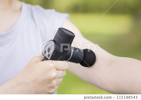 Young woman using a fascia release gun and massage gun outdoors Young woman using a fascia release gun and massage gun outdoors 115198543
