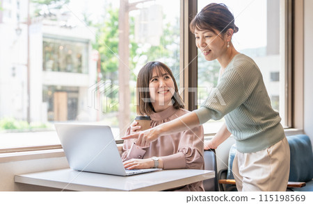 Businesswomen having a meeting and educating others while using a computer in an office cafe 115198569