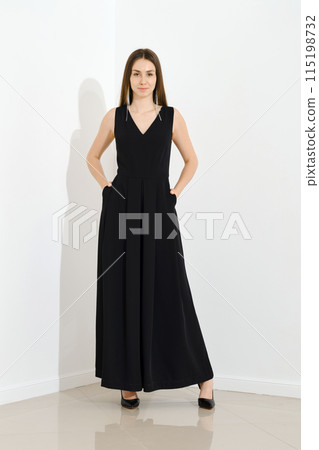 Stylish woman dressed in long sleeveless dress posing 115198732