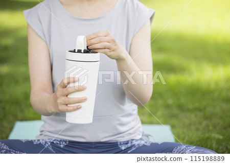年輕女子喝外面的蛋白質,外面的瑜珈形象 年輕女子喝外面的蛋白質,外面的瑜珈形象 115198889