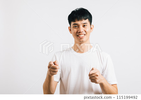 Portrait of a happy young man smiling while playfully pointing two fingers at the camera. Isolated on white background, he radiates optimism and a friendly demeanor. 115199492