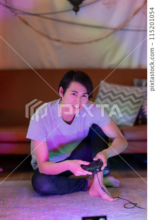 A young man playing games in the living room at night A young man playing games in the living room at night 115201054