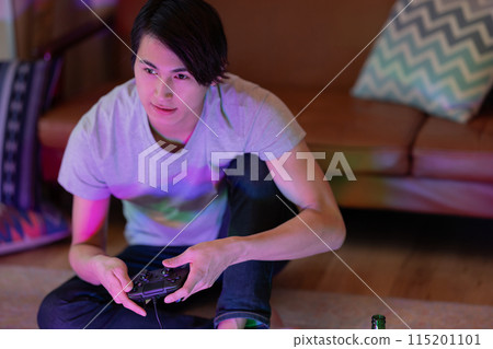 A young man playing games in the living room at night 115201101