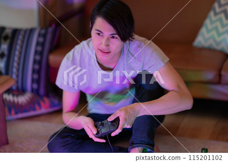 A young man playing games in the living room at night 115201102