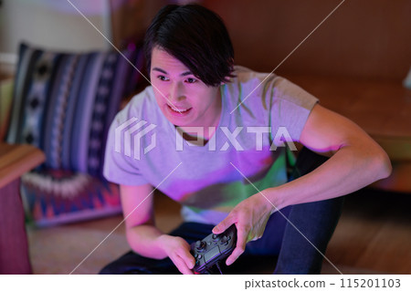 A young man playing games in the living room at night 115201103