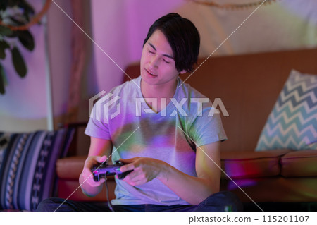 A young man playing games in the living room at night 115201107