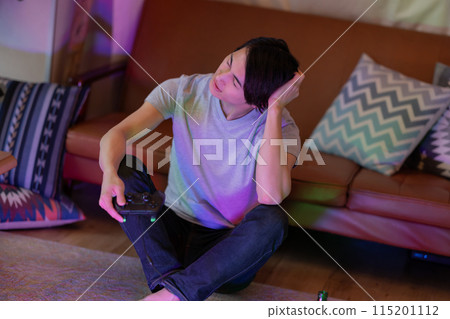 A young man playing games in the living room at night A young man playing games in the living room at night 115201112