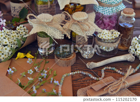Mystic still life with magic bottles, flowers and witchy ritual objects on old table. Occult, esoteric, wicca and divination concept. No foreign language, all symbols are fictional Mystic still life with magic bottles, flowers and witchy ritual objects on old table. Occult, esoteric, wicca and divination concept. No foreign language, all symbols are fictional 115202170