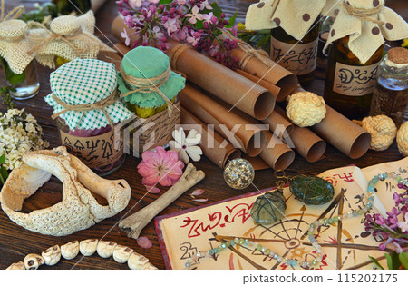 Mystic still life with magic book of spells, paper scrolls and witchy ritual objects on old table. Occult, esoteric, wicca and divination concept. No foreign language, all symbols are fictional 115202175