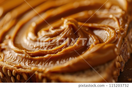 Closeup of smooth peanut butter spread on a slice of toast with sesame seeds 115203732
