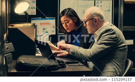 Law officers reading confidential folders in archive room at private company, gathering information to conduct investigation. Detectives create timelines based on archived records. Camera A. Law officers reading confidential folders in archive room at private company, gathering information to conduct investigation. Detectives create timelines based on archived records. Camera A. 115204137