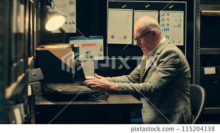Senior private agent studying federal statements and case details to connect the dots, researches legal precedents. Law officer reinvestigating archived cases based on new evidence. Camera A. 115204138
