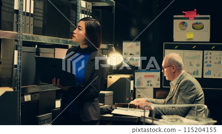 Private investigator organizes archived files for easy access, searching for old file cases to cross reference data. Law enforcement agent looking for classified folders in archive room. Camera A. 115204155