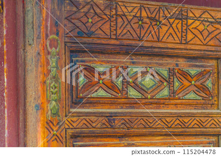 Big old wooden door decorated with various symbolic signs carved directly on the canvas of massif. Example of exterior and interior decoration of entrance lobbies in different cultures around world Big old wooden door decorated with various symbolic signs carved directly on the canvas of massif. Example of exterior and interior decoration of entrance lobbies in different cultures around world 115204478