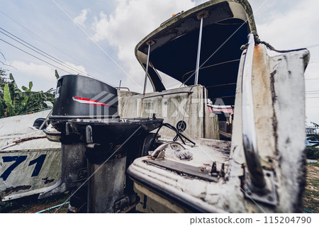 Old and rusty motor boats on a landfill surrounded by tropical forest 115204790