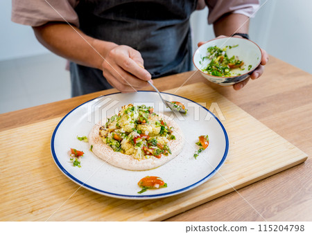 Chef at the kitchen preparing bean porridge with cauliflower and vegetables Chef at the kitchen preparing bean porridge with cauliflower and vegetables 115204798
