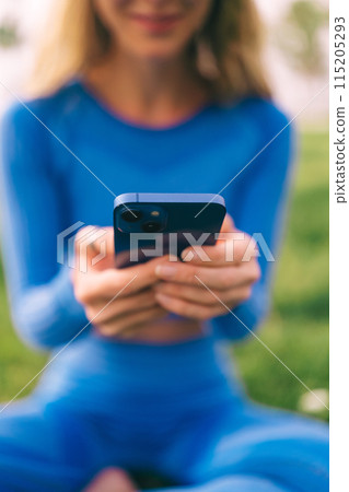Fitness woman using mobilephone while exercising. Smiling woman doing stretching workout Fitness woman using mobilephone while exercising. Smiling woman doing stretching workout 115205293