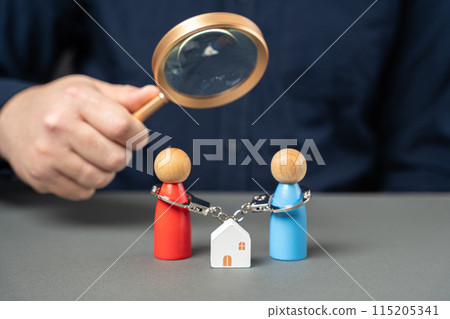 Dividing property after divorce. legal consultation. determine ownership. Divorce proceedings. A man holds a magnifying glass over a handcuffed couple standing near a house. Dividing property after divorce. legal consultation. determine ownership. Divorce proceedings. A man holds a magnifying glass over a handcuffed couple standing near a house. 115205341