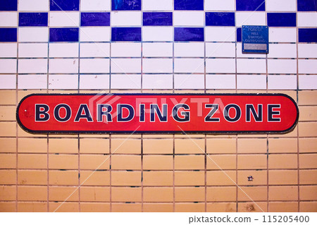 BOARDING ZONE in black and red on tile wall split between tan and white with blue pattern 115205400